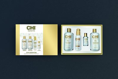 Geöffnetes CHI Keratin Set: links die goldene Geschenkschachtel, rechts die vier Flaschen darin, auf dunkelblauem Grund.